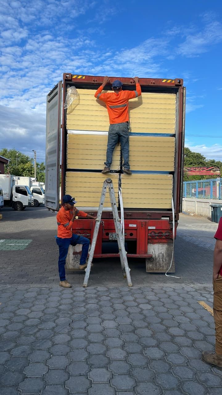Dos trabajadores cargan paneles en un contenedor sobre remolque